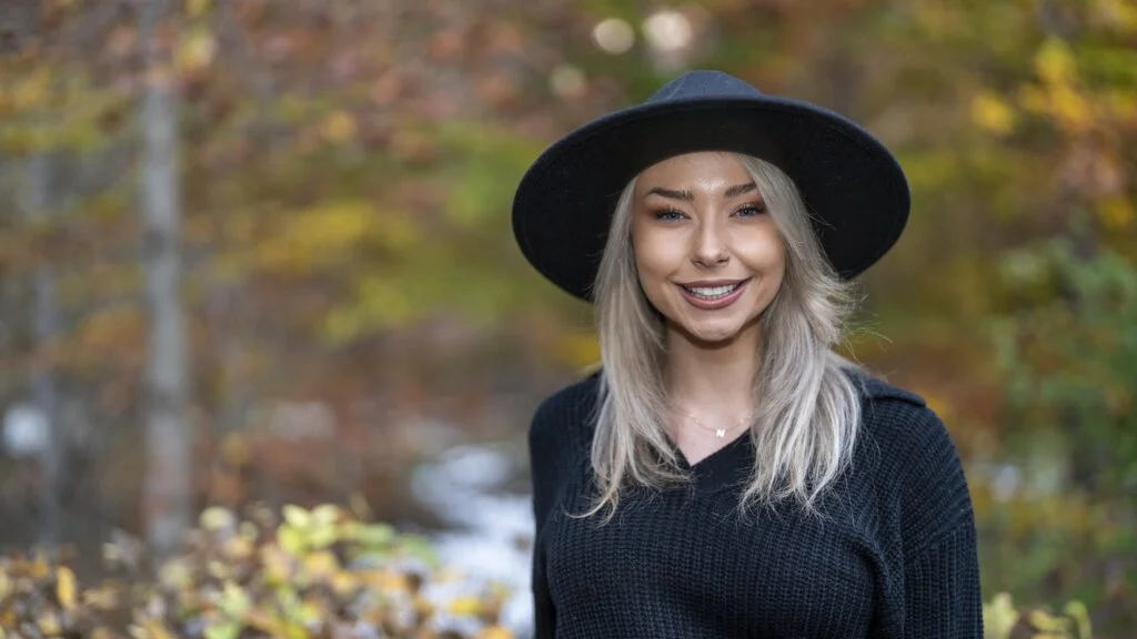 A woman wearing a black hat in the woods.
