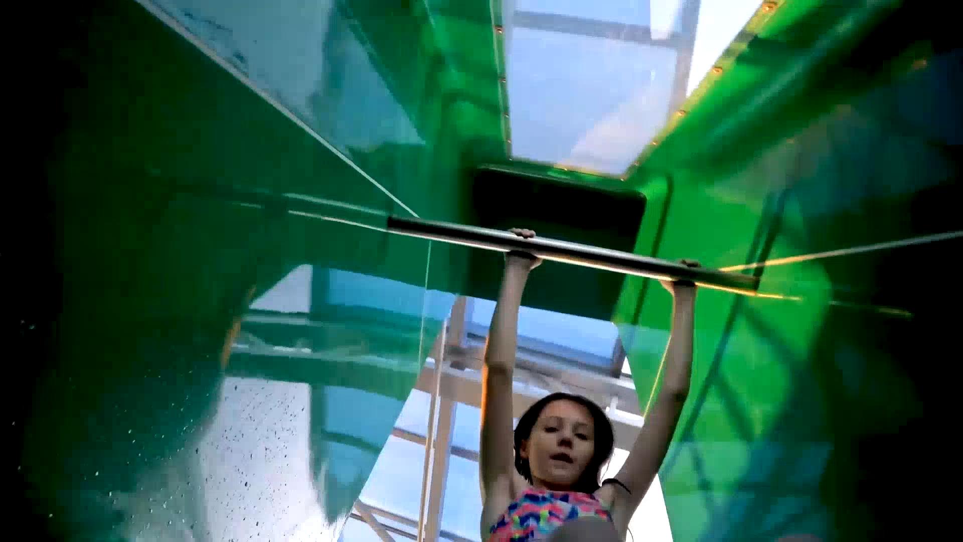 A girl in a bikini on a green slide.